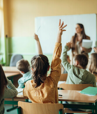 elementary students in classroom hand raised