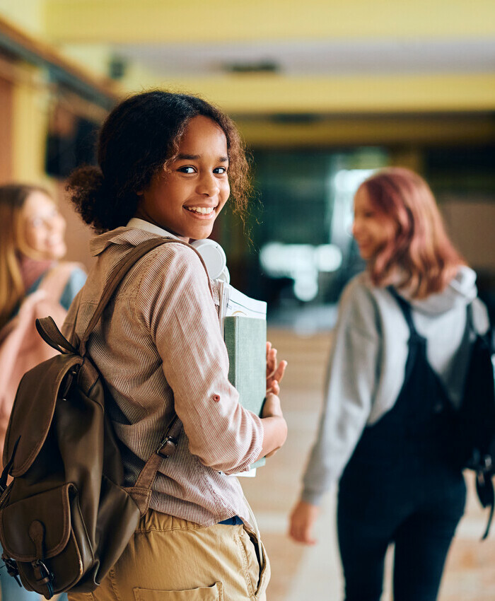 student looking to camera while walking with classmates in hallway